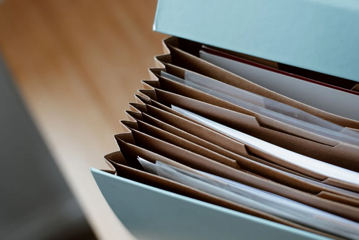 An open accordion file on a wooden table, every paper filed in order